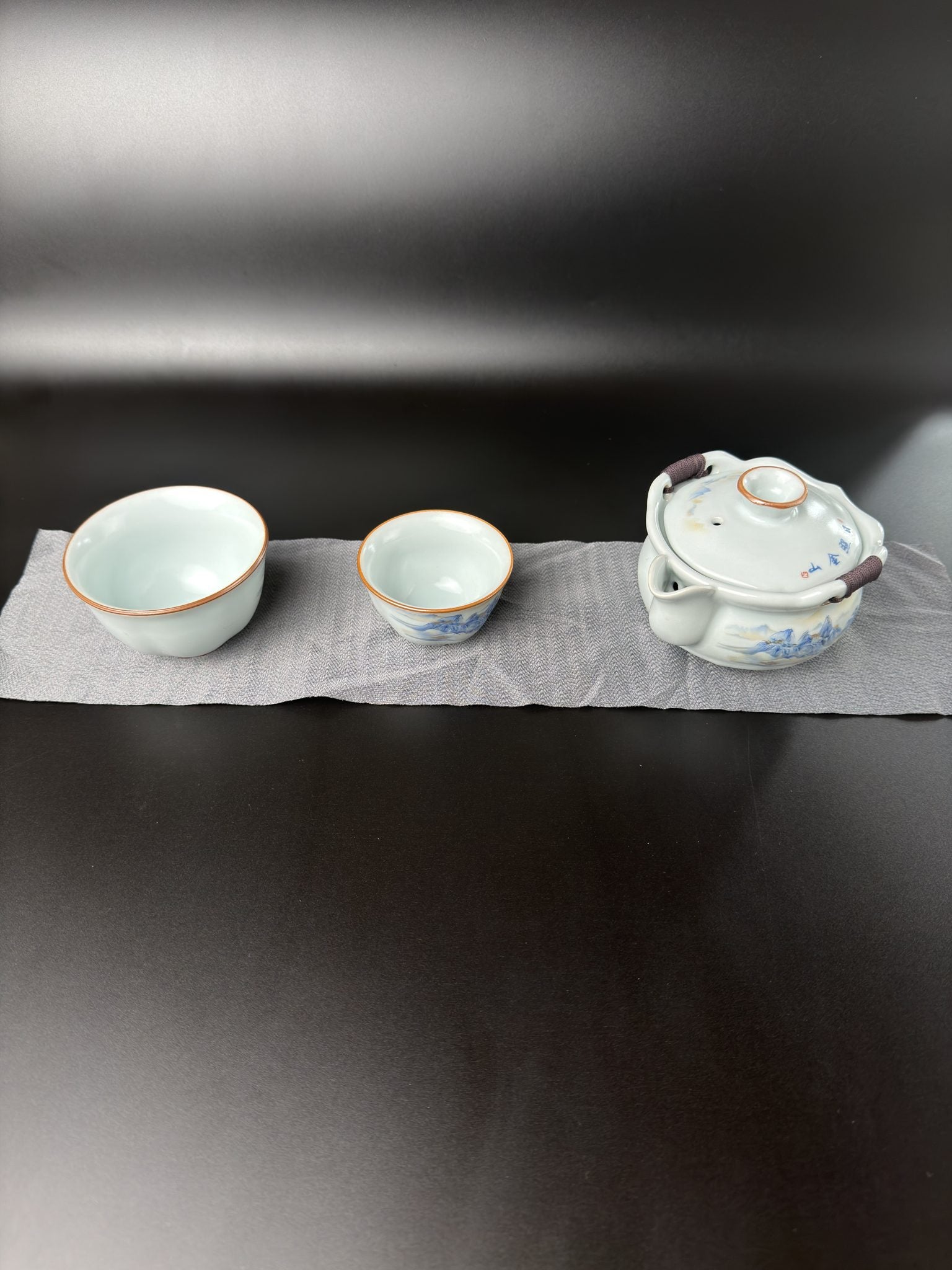 Service à thé de voyage Daothé, petite théière en porcelaine et deux tasses de tailles différentes sur un chiffon