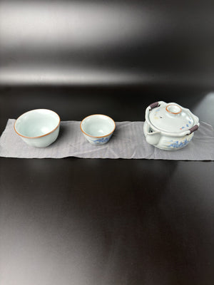 Service à thé de voyage Daothé, petite théière en porcelaine et deux tasses de tailles différentes sur un chiffon